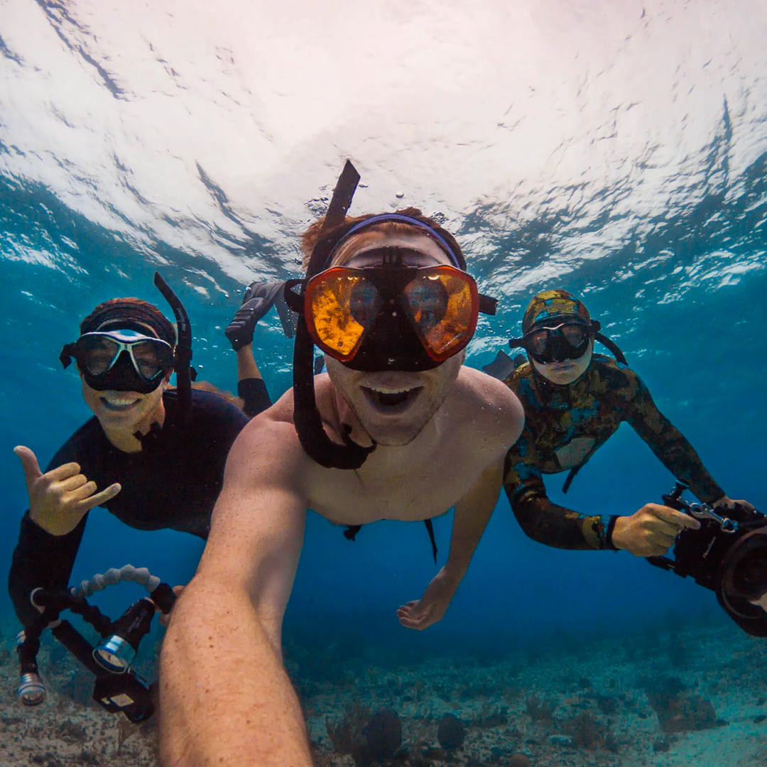 three peoples snorkeling with underwater camera