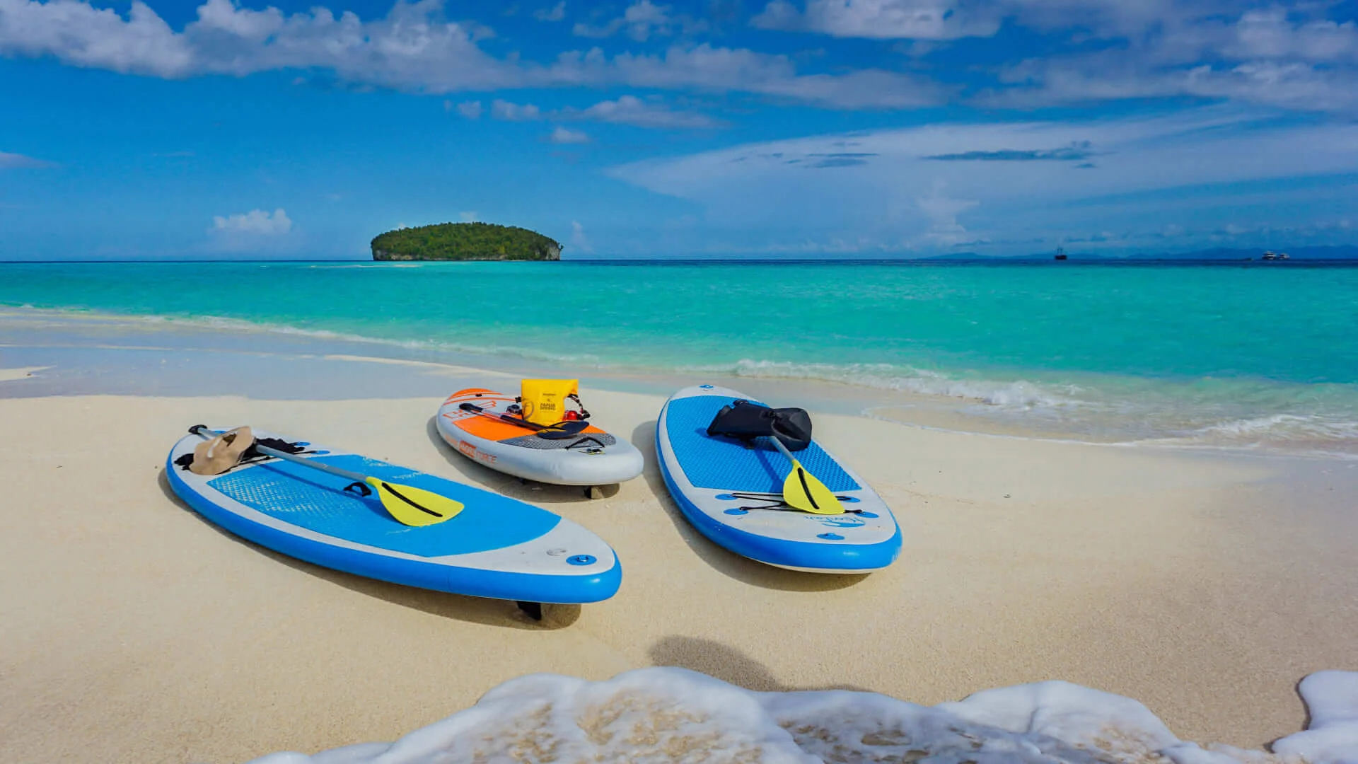 three stand-up paddleboard at the shore of sea with clear blue water and sky in Raja Ampat